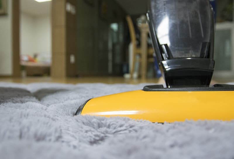 Yellow and black upright vacuum on gray fleece rug inside room