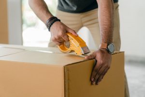 A man taping a cardboard box.