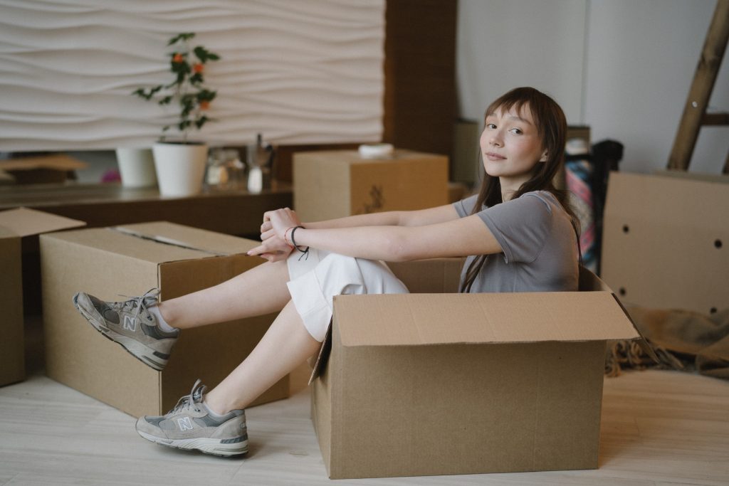 A woman sitting in a cardboard box.