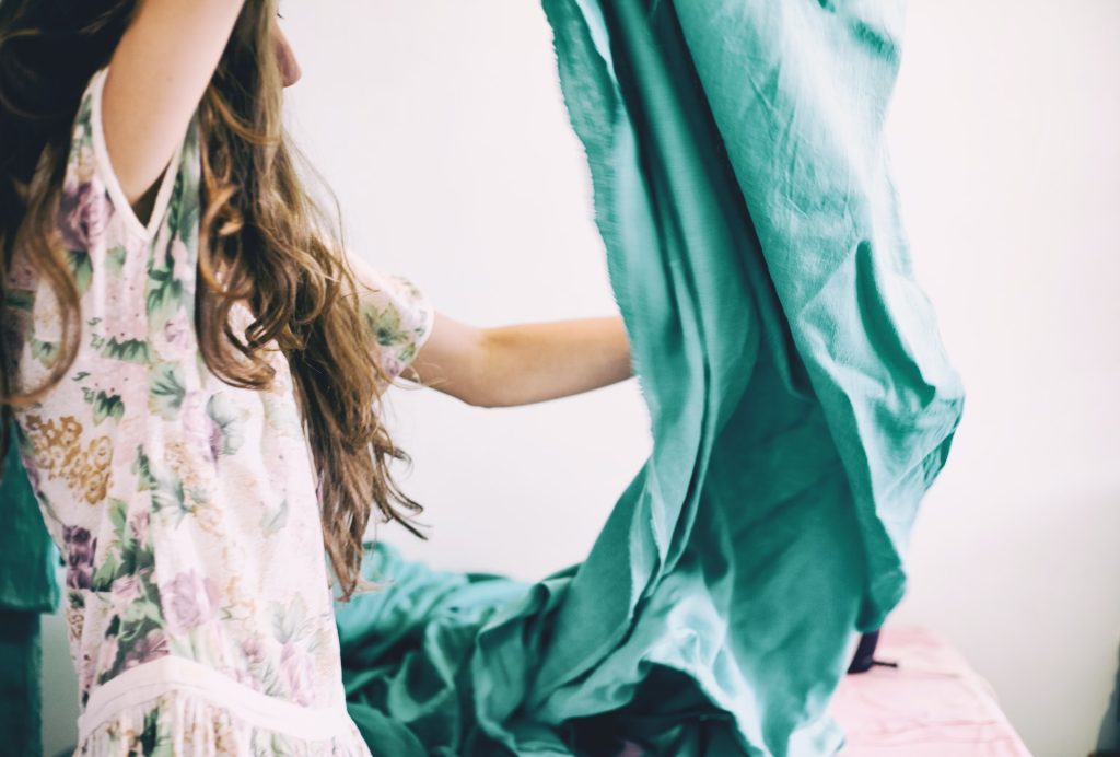 women holding bead sheets because it’s one of the things you should clean every week